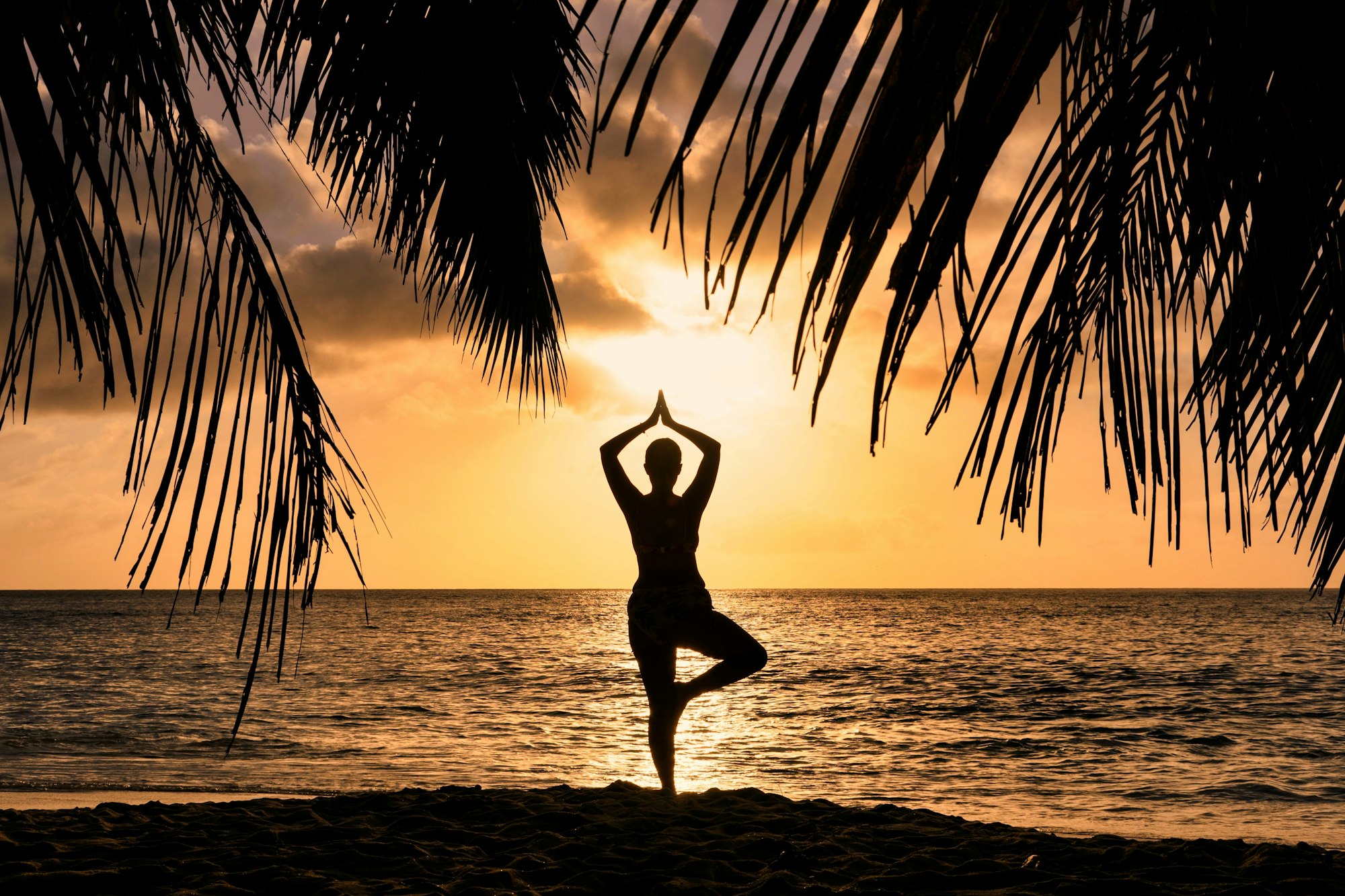 Silhouette of a woman in a yoga pose at sunset.