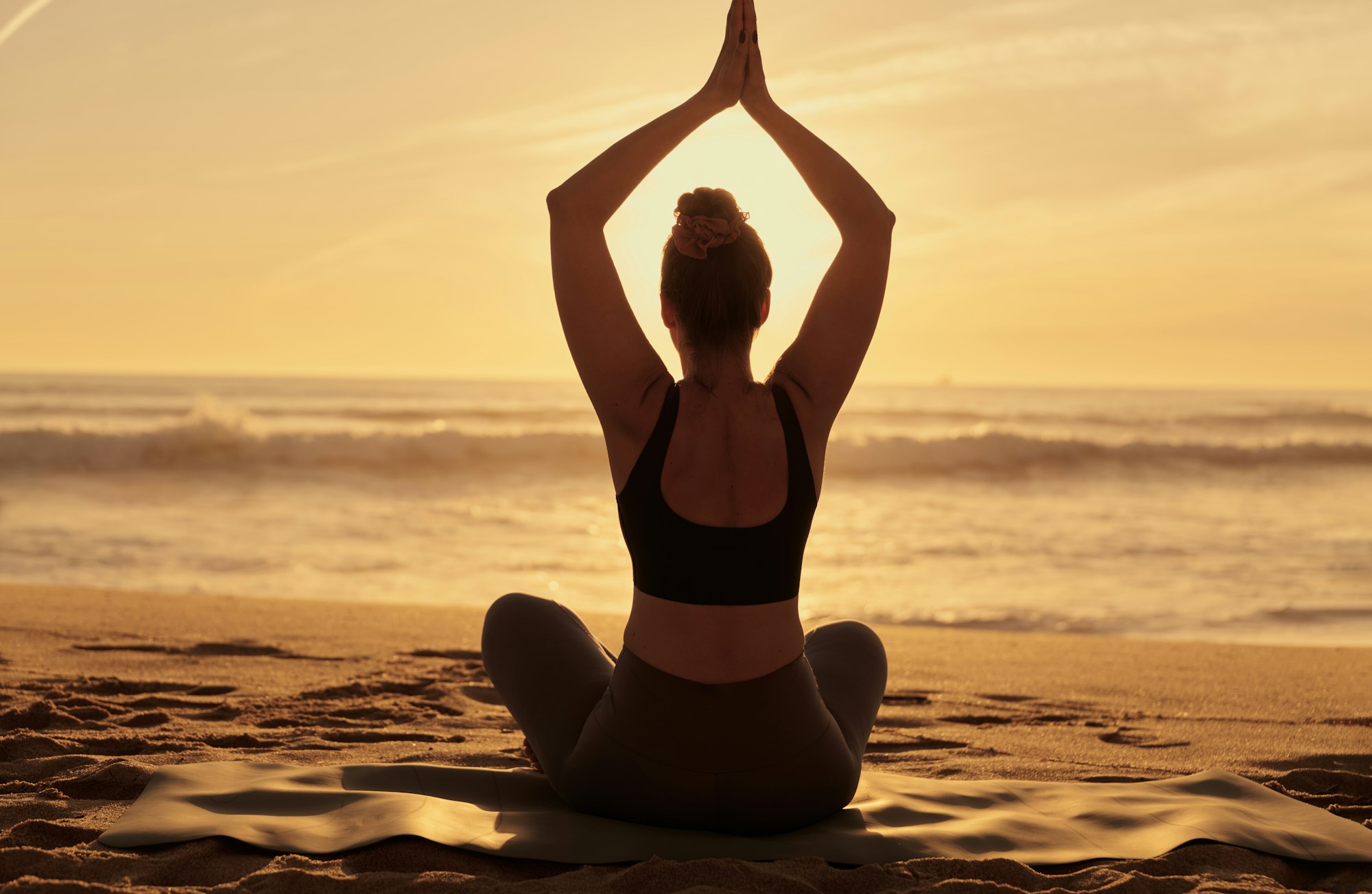 Slim woman doing yoga with raised arms