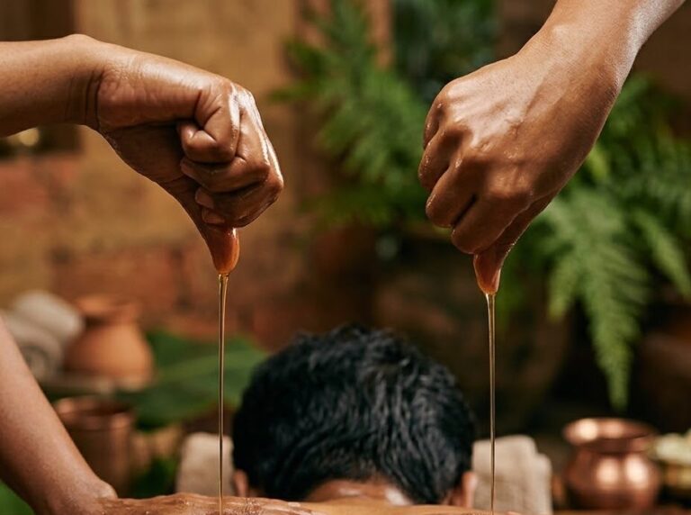 Two therapists pouring warm medicated oil over the back during Pizhichil