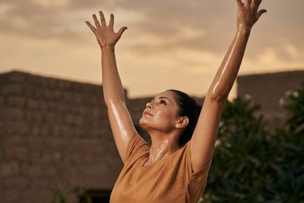Woman stretching her arms upward outdoors at sunset