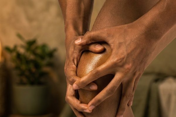 Hands holding a painful knee joint