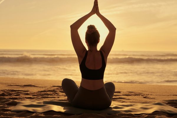 Slim woman doing yoga with raised arms